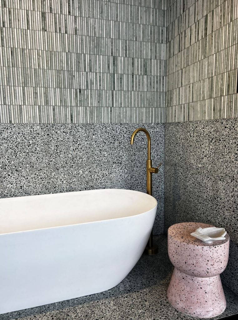 black and white  linear and speckled tiles with white  bath and pink  speckled stool