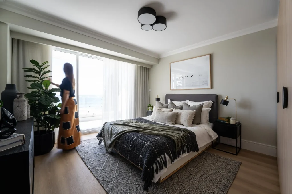 woman opening the curtains in a texturally styled bedroom - Manly, Sydney